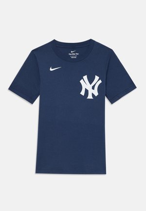 T-shirt en coton bleu marine à manches courtes. Présente un logo Nike blanc sur la poitrine gauche et un logo des New York Yankees blanc sur le devant.