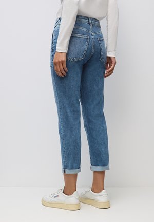 Lyseblå denim jeans med tapered fit, opfoldede bukseben, to baglommer og en mellemhøj talje. Sammen med hvide sneakers.