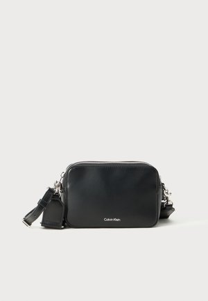 Sac bandoulière en cuir noir de forme rectangulaire, avec des accessoires en métal argenté, une bandoulière réglable et un logo de la marque embossé à l'avant.