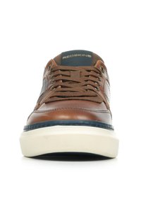 Sneaker in pelle marrone con suola bianca e blu navy. Presenta lacci rotondi marroni, cuciture in evidenza e logo sulla linguetta.