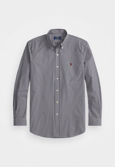 Μπλούζα μακρυμάνικη ριγέ μπλε και λευκή από βαμβάκι, με καμπύλη γιακά και λευκά κουμπιά, καθώς και ένα μικρό κόκκινο λογότυπο στο στήθος.