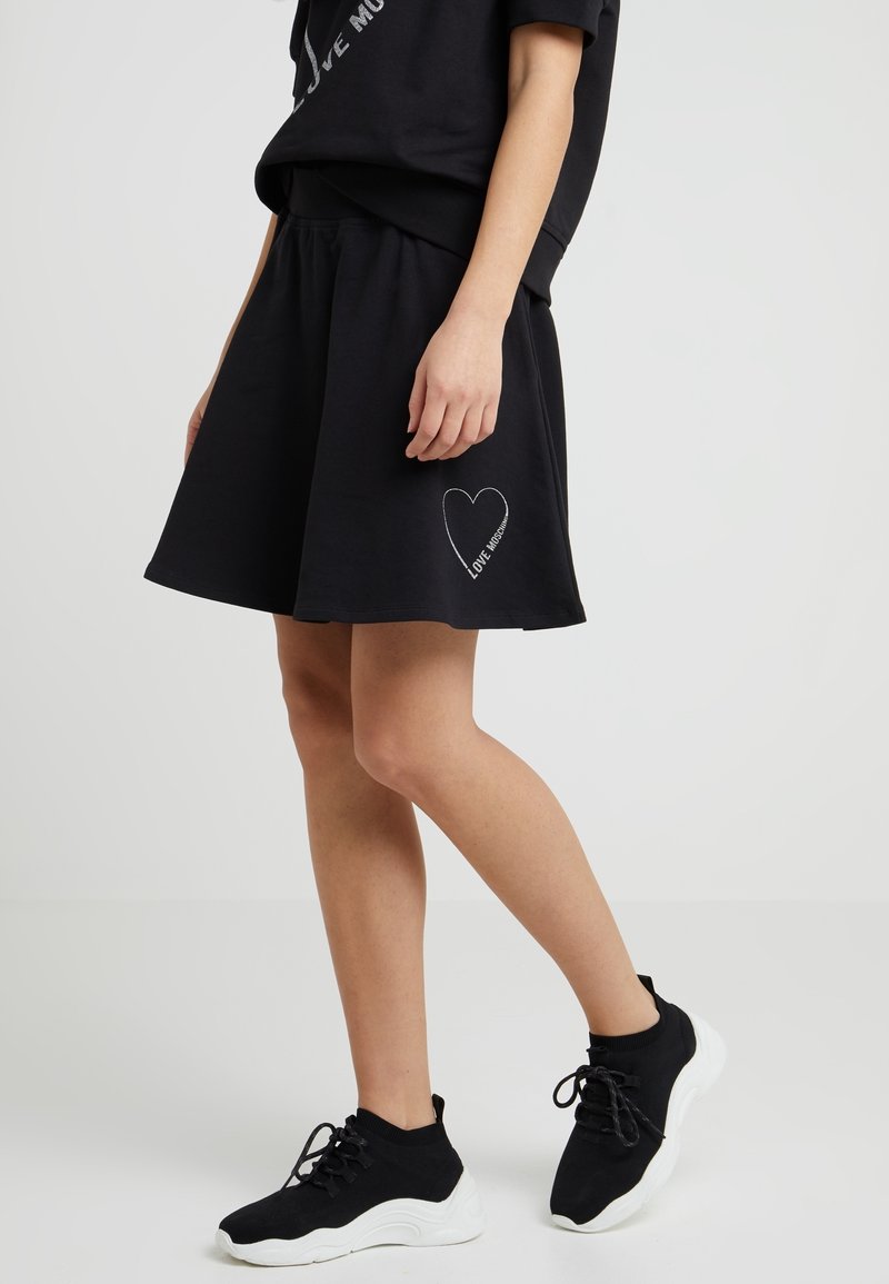 Svart bomullsskjorta med en utsvängd design och sidoficka, prydd med en vit hjärn- grafik med texten "LOVE". Matchad med svarta sportskor.