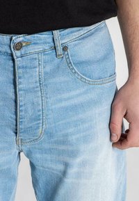 Ljusblå denimjeans med slim fit, som har fem fickor, kontrasterande sömmar och knapp- och dragkedjestängning i midjan.