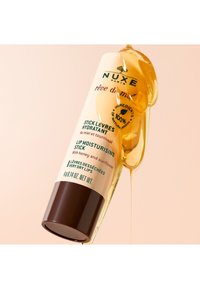 Balsam do ust NUXE w białej tubce z brązową podstawą, z zielonym napisem i kroplą miodu. 100% naturalne składniki, 14g.