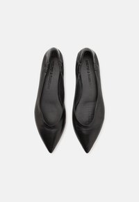 Bailarinas de cuero negro con diseño de punta afilada, textura suave y abertura flexible. La suela presenta el logotipo de la marca grabado en el interior.