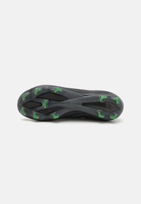 Semelle de chaussure de sport noire avec une surface texturée, mettant en avant des accents verts et un design épuré pour l'adhérence et la stabilité.