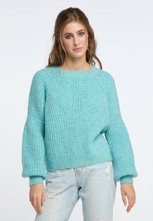 Pulover tricotat teal, cu un design texturat și dantelat. Are un guler rotund și mâneci tip balon. Este asortat cu blugi deschiși, puțin deteriorați.