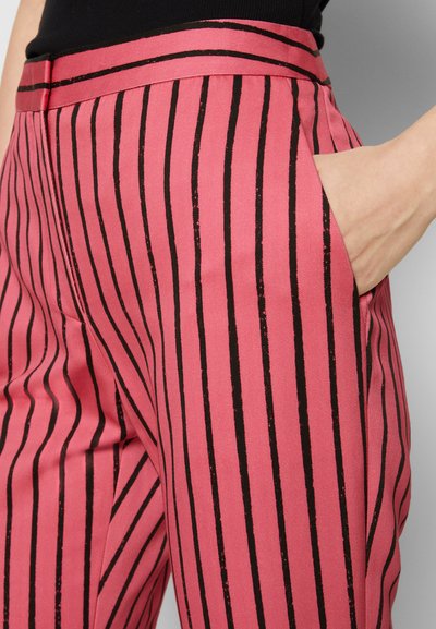 Calças listradas em rosa com riscas verticais pretas, uma textura suave e bolsos laterais. A cintura é de um rosa sólido.