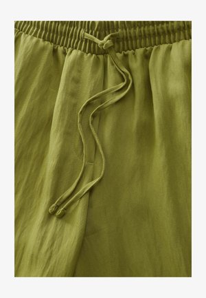 Pantaloni verde oliva realizzati in tessuto leggero. Caratterizzati da una vita elastica e coulisse. Texture liscia con una morbida caduta.
