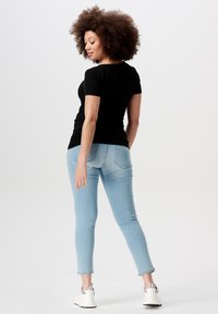 Sort ribbet t-shirt i kortærmet version, parret med lyseblå skinny jeans. Det afslappede outfit afsluttes med hvide sportssneakers.