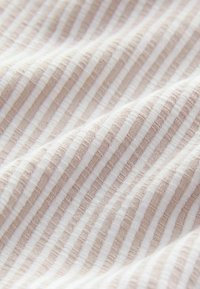 Light fabric with alternating thin stripes of beige and white, featuring a soft, textured surface. The stripes create a subtle pattern.