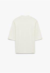 Camiseta de manga corta color crema con cuello redondo y un ajuste relajado. Textura suave, diseño minimalista y sin patrones o acentos visibles.