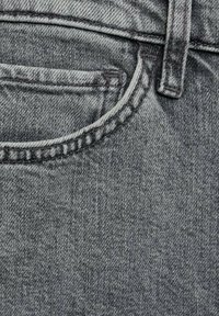 Siva denim tkanina z vdelanom žepnim detajlom, vidno teksturo in klasično petžepno zasnovo. Enotna barva z manjšimi odstopanji.