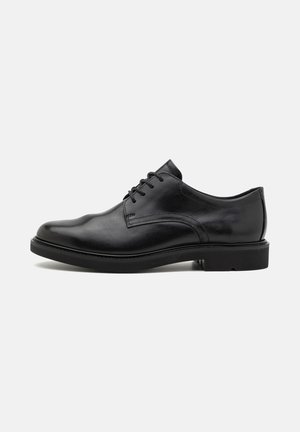Zwarte leren herenschoenen met vetersluiting en lage hak, zijaanzicht tegen een effen lichte achtergrond.