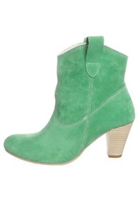 Bottine en daim vert avec talon effilé, bout arrondi, col matelassé et surpiqûres blanches le long du côté et du coup-de-pied.