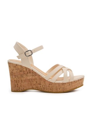 Sandalias de cuña beige con múltiples correas, plantilla en textura de corcho y correa de tobillo con hebilla. Acabado liso con suela plana.