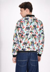 Multifarvet bomberjakke med panda- og blomsterprint, sort ribkrave og manchetter, letvægtsstof med en glansfuld overflade.