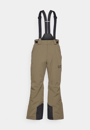 Pruunid lumepüksid mustade reguleeritavate rihmadega ja mustade tugevdatud kangast plaastritega siseküljel, millel on reitel väike logo.