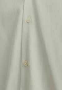 Light green shirt with a textured fabric, featuring two buttons in a contrasting cream color, displaying a simple, clean design.