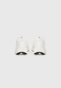 White sneakers with mesh and synthetic overlays, featuring a black outsole, pull tab, and embossed "DIESEL" logo on the heel.
