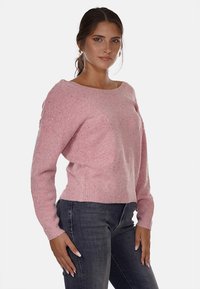 Maglione rosa a maglia con scollo relax, maniche lunghe e finitura testurizzata, abbinato a jeans di denim scuri.