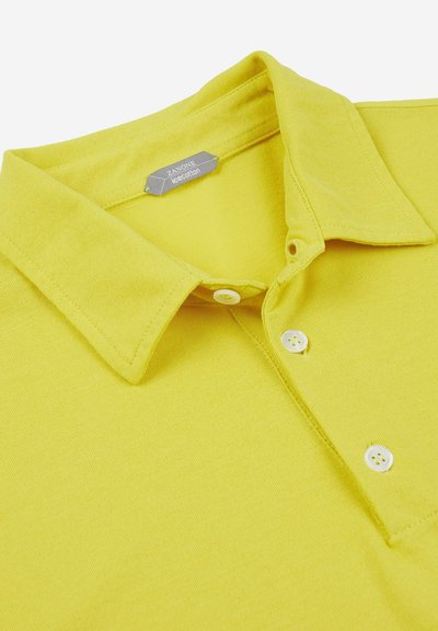 Geel poloshirt van zachte katoen, met een standaardkraag, drie witte knopen en een klein merkembleem op de kraag.