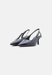 Μαύρες γόβες slingback από δέρμα με προστατευτικό γυαλιστερό φινίρισμα, μυτερή μύτη και χαμηλό τακούνι. Διαθέτουν λεπτό λουράκι με μεταλλικό αγκράφα διακοσμητικό.