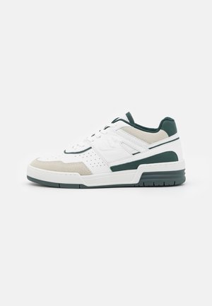 Biały niski sneaker z zielonymi i beżowymi akcentami, sznurowany z przodu, z perforowanymi detalami po bokach i na czubku.