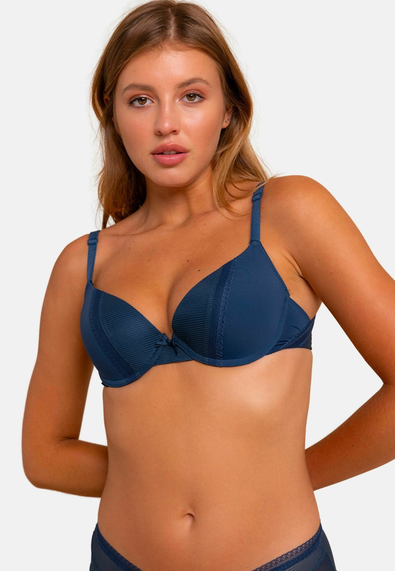 Soutien-gorge rembourré bleu marine avec texture côtelée, bord en dentelle le long du bord et bretelles réglables. Détail de nœud à l'avant pour une touche décorative.