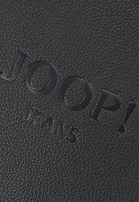 Pelle nera testurizzata con logo in rilievo "JOOP! JEANS". Presenta un motivo distintivo e un design elegante.