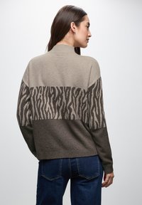 Strickpullover mit einem Farbblockdesign in Beige und Braun, ergänzt durch Akzente im Zebra-Muster. Lange Ärmel, gerippter Kragen und weiche Textur.