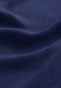 Navy blue fabric featuring a soft, smooth texture with a slight sheen and subtle surface pattern, draping gently in folds.