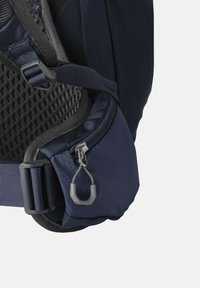 Coin d'un sac à dos bleu marine en tissu texturé, doublure en mesh, poche zippée et détails de quincaillerie gris, mettant en valeur des bretelles robustes et des bords lisses.