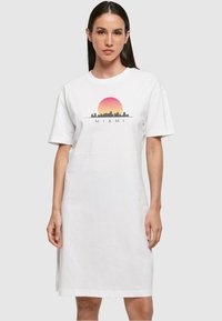 Fehér pamut pólóruha rövid ujjakkal, elülső részén színes Miami látképet és gradient napmintázatot ábrázoló grafikával.