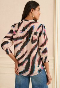 Blusa leggera e morbida di colore rosa con stampa animale astratta in nero e blu. Presenta maniche a sbuffo e polsini elasticizzati.