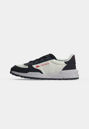 Adidași bărbați albi și negri Lacoste cu logo roșu, panouri laterale matlasate și talpă groasă, arătați din profil pe fundal alb.