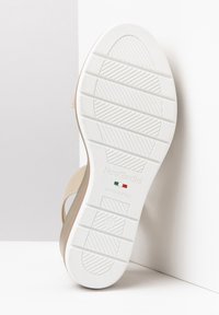 Sandale beige avec une semelle en caoutchouc blanche, présentant un motif de semelle texturé. La semelle intérieure porte la marque "NeroGiardini" et la taille "37" en relief.