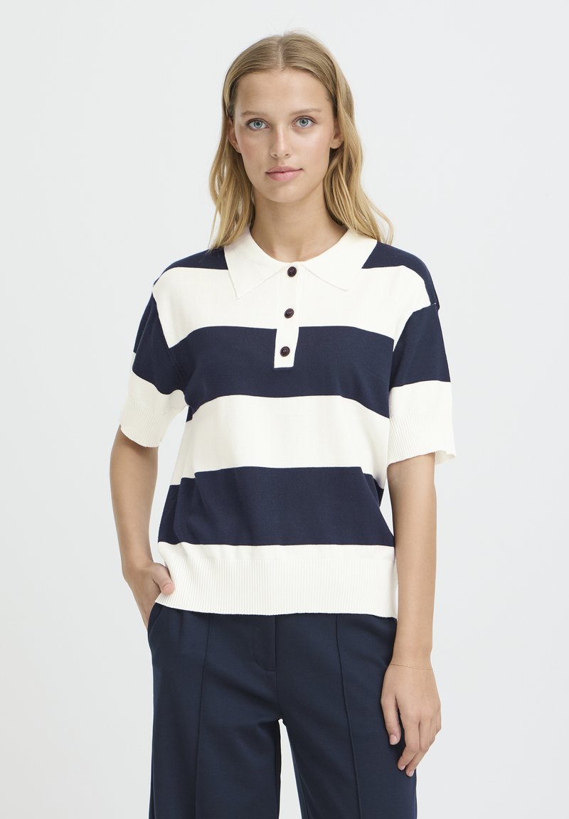 Pull polo à manches courtes rayé bleu marine et crème avec un col plat et une patte de boutonnage à trois boutons. Texture douce et détail de bord-côte à l'ourlet.