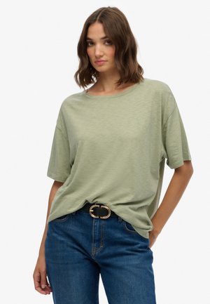 Lichtgroene T-shirt met korte mouwen van zachte stof, met een ontspannen pasvorm en ronde halslijn, gecombineerd met blauwe jeans en een zwarte riem.