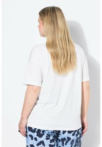 Wit katoenen T-shirt met een ontspannen pasvorm, voorzien van korte mouwen en een ronde hals. Het model draagt patroonblauwe broek.