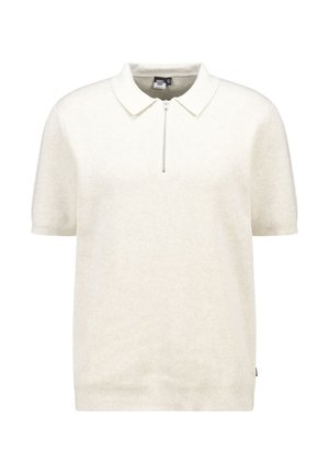 Polo shirt crème à manches courtes avec une texture côtelée, un col et une fermeture éclair demi-lune. Présente une petite étiquette sur le côté pour le branding.