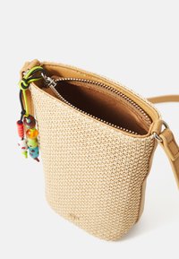 Bolsa tejida color marrón claro con un exterior texturizado y trenzado, y ribete de cuero. Cuenta con un cierre cremallera y acentos de cuentas coloridas adjuntas a la cremallera.