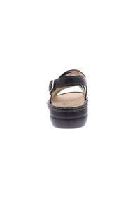 Sandal in pelle nera con una cintura regolabile, ampia zona per le dita e suola rialzata caratterizzata da dettagli intrecciati lungo i bordi.