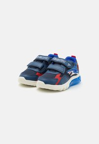 Pantofi sport albaștri cu accente roșii și panouri din plasă, având două benzi Velcro și un grafic cu un rechin pe lateral. Talpă din cauciuc.