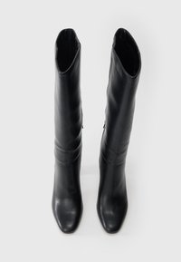 Μαύρες δερμάτινες μπότες που φτάνουν ως το γόνατο με κομψό σχέδιο, τετράγωνη μύτη και λεία υφή, με διακριτική λεπτομέρεια φερμουάρ στο πλάι.