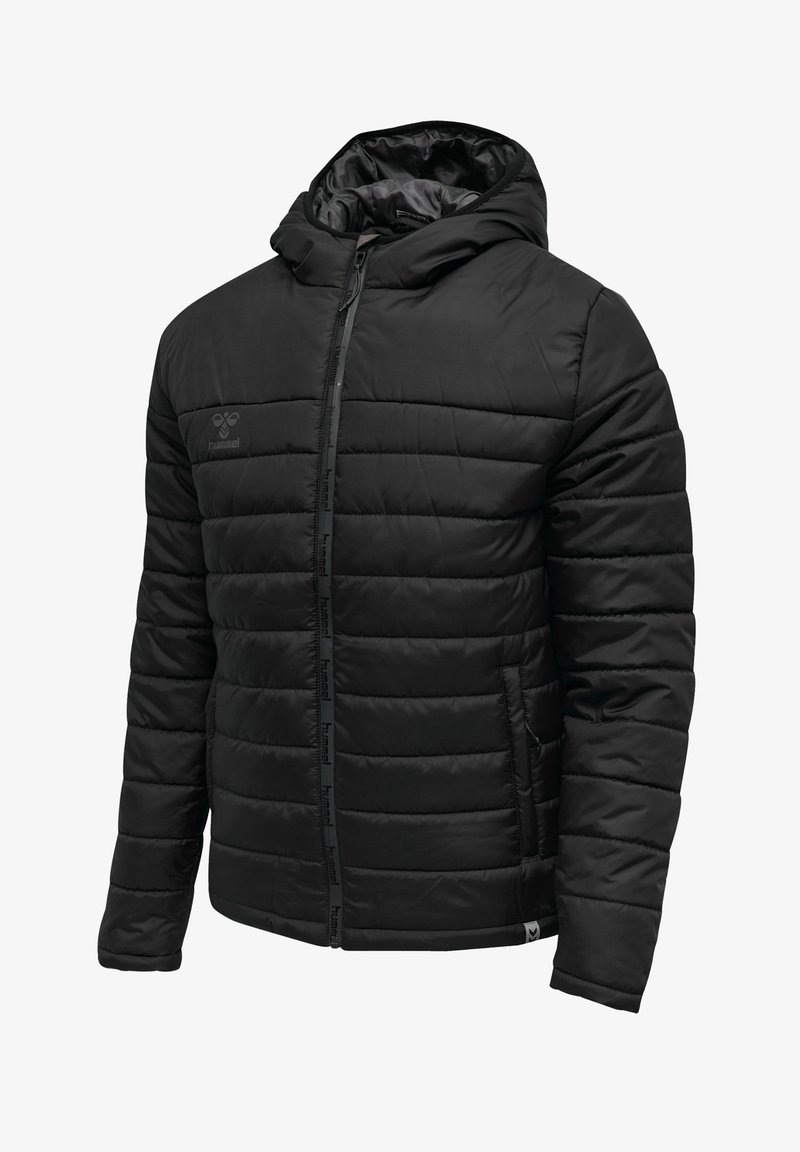 Veste noire matelassée à capuche avec fermeture éclair frontale, poches latérales et logo discret sur la poitrine, conçue pour le confort par temps froid.