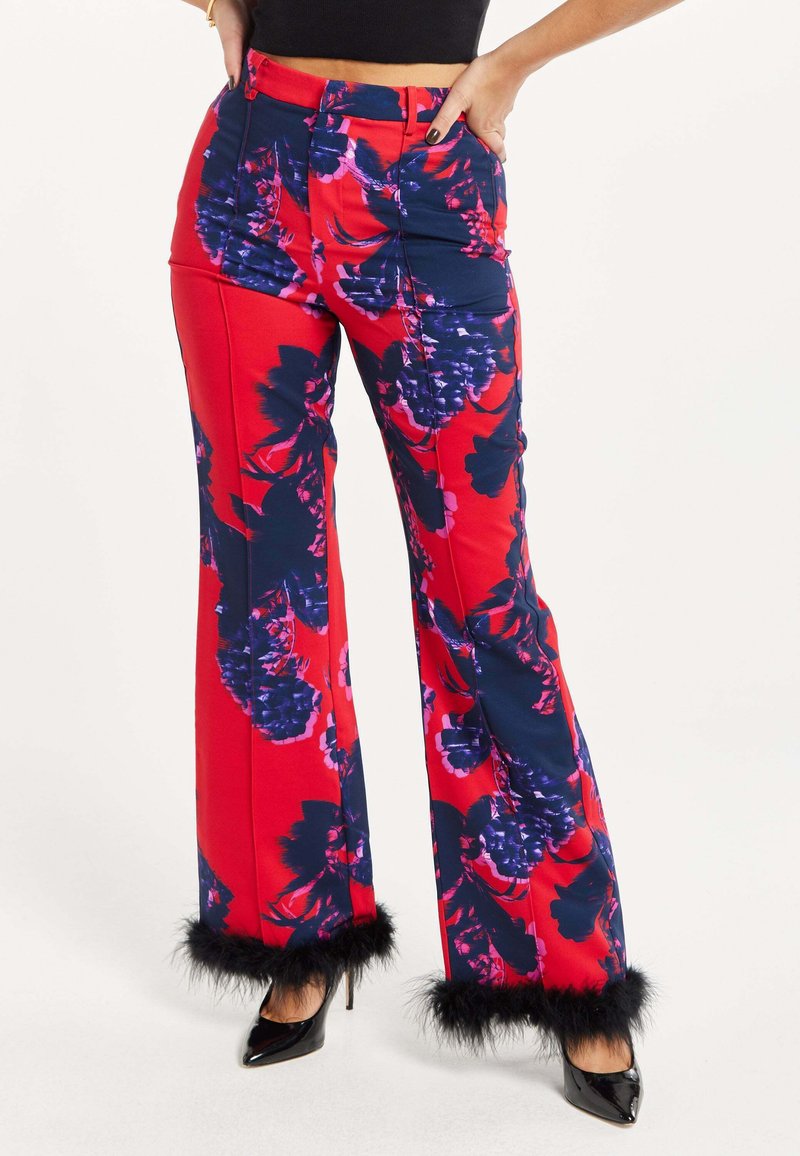Red floral-patterned pants with blue accents, wide leg design, and black faux fur trim at the cuffs. Features a high-waisted style.