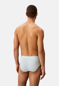 Slip da uomo azzurri con vita a contrasto. Il tessuto appare liscio e aderente. La vista posteriore mostra un design snello.