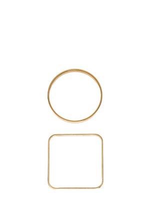 Anelli di metallo dorato, uno circolare sopra e uno quadrato con angoli arrotondati sotto, su uno sfondo bianco semplice.