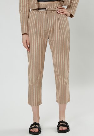 Pantaloni a righe color sabbia con gamba affusolata, pieghe frontali, vita con cintura e lunghezza cropped, abbinati a sandali neri a scivolo.